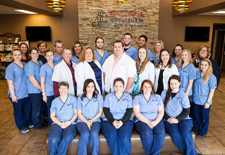 The entire care and administrative team of Rose Rock Veterinary Hospital & Pet Resort posing in the lobby wearing blue or white scrubs in Norman, OK.